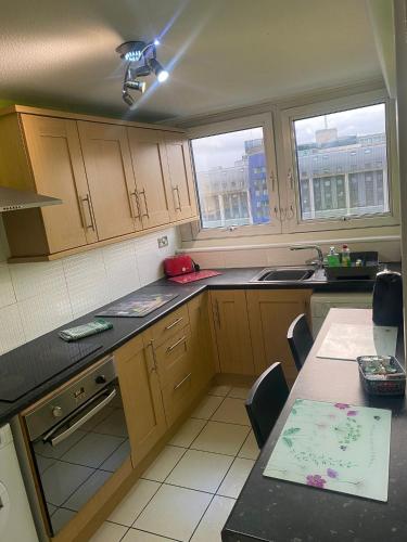 a kitchen with wooden cabinets and a table and two windows at "Snooze Central" - City Centre Apartments above Victoria Centre Shopping Centre with full Kitchen in Milton Street - up to 4 Beds - most Central Location next to the Hilton Hotel - Parking for Cars or Vans from Five Pounds a day - Sunday 1pm Check-Out in Nottingham