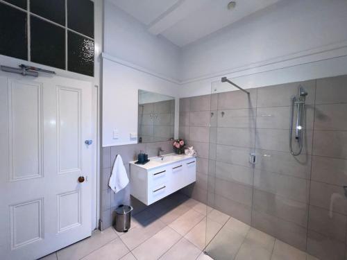 a bathroom with a shower and a sink and a mirror at Arthurton Central in Hobart