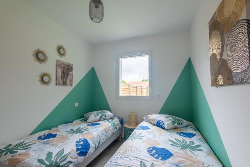 - 2 lits dans une chambre aux murs verts et blancs dans l'établissement Maison avec jacuzzi, à Biscarrosse