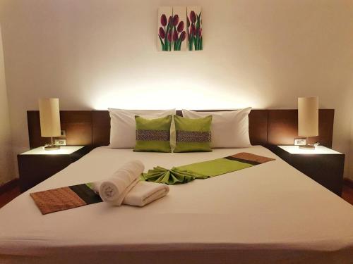 1 cama con 2 toallas y 2 lámparas. en Palm Inn, en Ban Na Phong