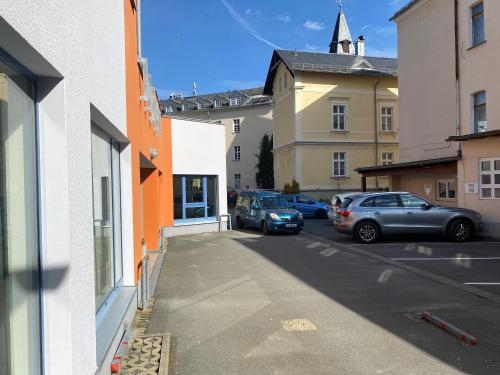 two cars parked in a parking lot next to buildings at FeWo Roland Ranft direkt am Kurpark Barrierearm 60qm in Bad Elster