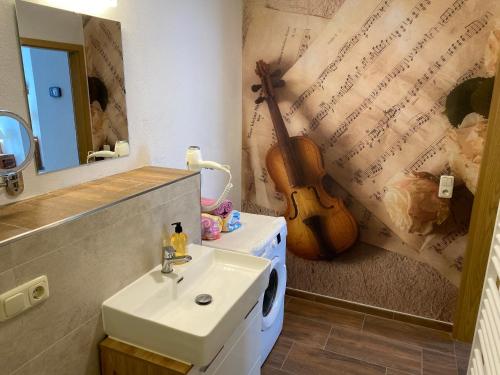 a bathroom with a sink and a guitar on the wall at FeWo Roland Ranft direkt am Kurpark Barrierearm 60qm in Bad Elster