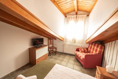 a attic room with a couch and a tv at Pensión QuintAna in Prellezo