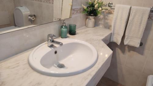 een badkamer met een witte wastafel en een spiegel bij Casa do Mar in Salema