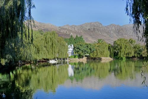 a house on the lake with mountains in the background at Farm Lorraine Lake Cottage, Loft Cottage and Garden Cottage in Franschhoek