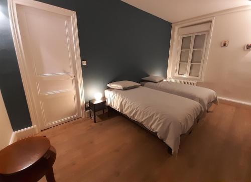 een slaapkamer met 2 bedden en een tafel en een deur bij Bulle d'Ardenne in Charleville-Mézières