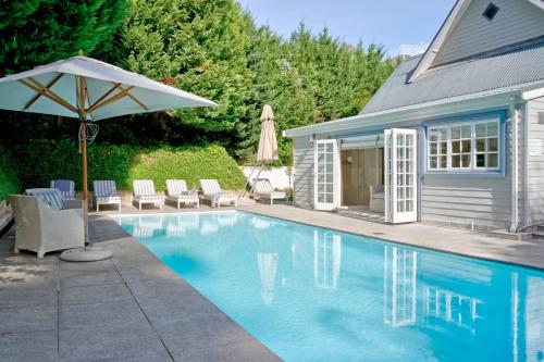 une piscine avec un parasol et des chaises ainsi qu'une maison dans l'établissement Farm Lorraine Lake Cottage, Loft Cottage and Garden Cottage, à Franschhoek