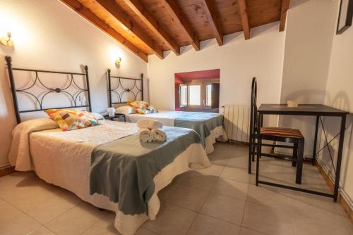a bedroom with two beds and a table in it at Pensión QuintAna in Prellezo