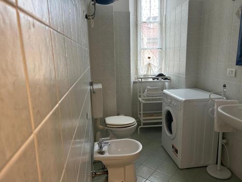 a white bathroom with a toilet and a sink at Casa L'abbraccio in Livorno