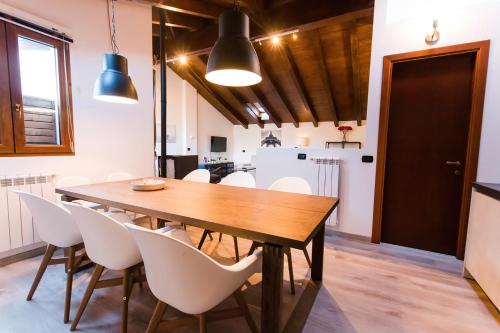 uma sala de jantar com uma mesa de madeira e cadeiras brancas em Bella Camelia - Lago di Como em San Siro