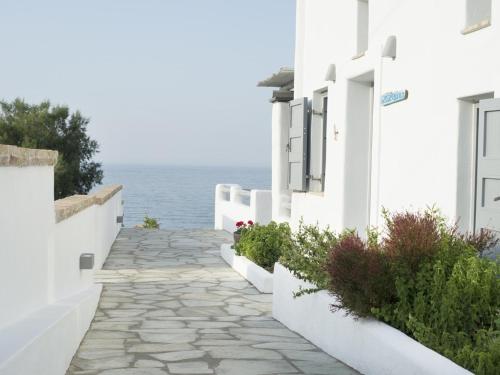 a stone walkway next to white buildings and the ocean at Ianthi Boutique Guesthouses Skyros in Skiros