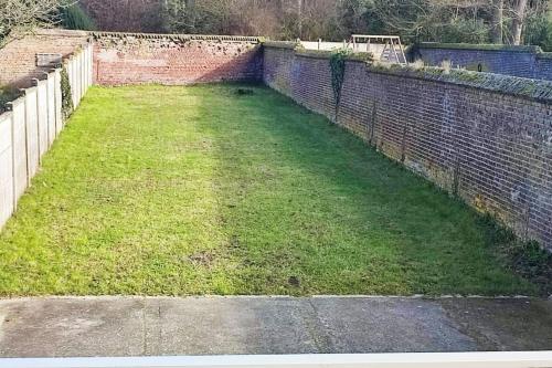 a large yard with a brick wall and green grass at LeRelaisdOdile * Grand T3 * Hyper Centre in Cambrai