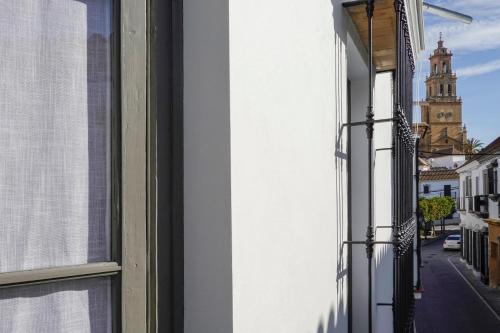 una ventana abierta de un edificio con una torre de reloj en Hospederia Santa Clara, en Utrera