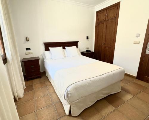 una camera da letto con un grande letto con lenzuola e cuscini bianchi di Hostal La Muralla a Zahara de los Atunes
