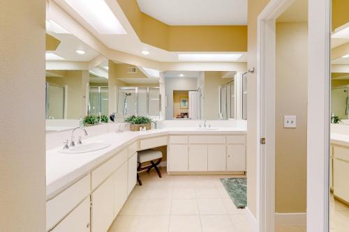 a bathroom with two sinks and two mirrors at The Gem of Palm Desert in Palm Desert