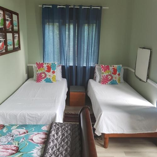 a room with two beds and a window with blue curtains at Fishermen s Cave in Port St Johns