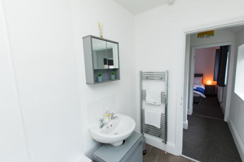 a white bathroom with a sink and a mirror at K Suites - Ely Road in Arksey