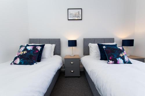twee bedden naast elkaar in een kamer bij K Suites - Ely Road in Arksey