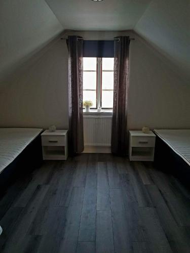 Cette chambre mansardée comprend 2 lits et une fenêtre. dans l'établissement Lilla lägenheten, à Broddetorp