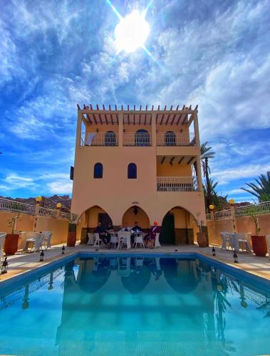 a villa with a swimming pool in front of a building at Dar izem in Tafraoute