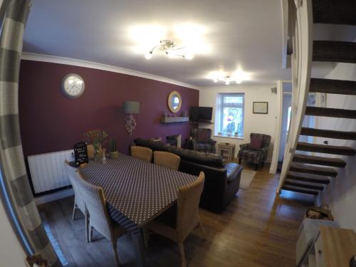 a dining room and living room with a table and chairs at Bodeinion in Nefyn