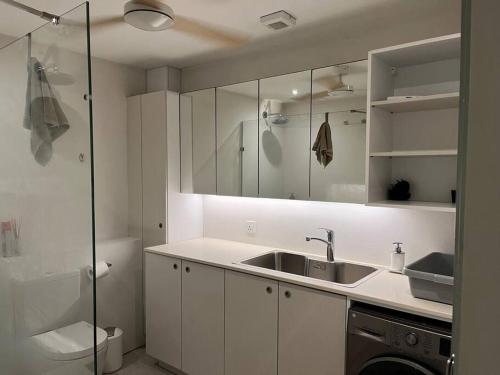 a white kitchen with a sink and a shower at Beachfront Apartment in Tamarin