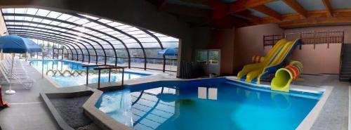 - une grande piscine avec toboggan dans un bâtiment dans l'établissement Camping VITAMIN DIEPPE, à Saint-Aubin-sur-Scie
