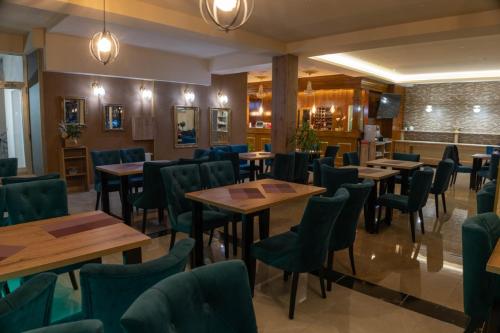 a restaurant with wooden tables and green chairs at HOTEL Villa Grande in Bugojno