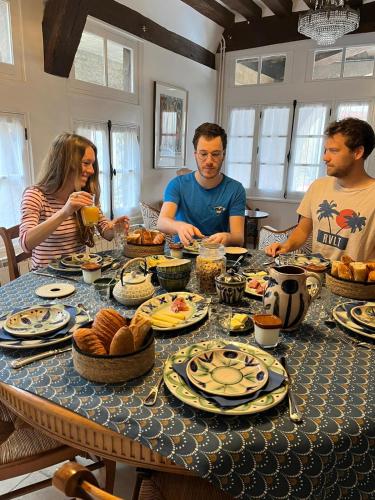 een groep mensen die rond een tafel zitten met eten bij La Maison des Corporations in Noyers-sur-Serein