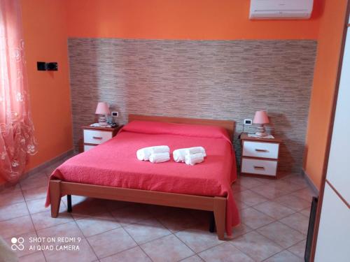 ein Schlafzimmer mit einem roten Bett mit zwei Handtüchern darauf in der Unterkunft B&B Tanca Marracconi Teulada in Teulada