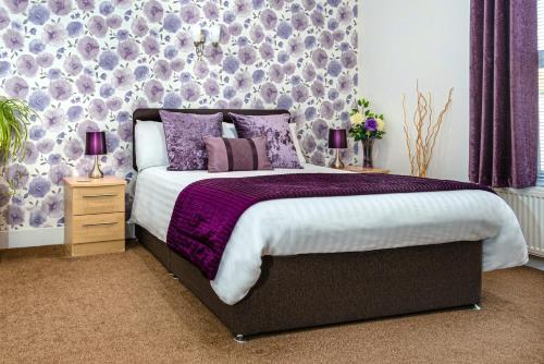 a bedroom with a large bed with purple pillows at The Richmond Bed and Breakfast - Adults only in Shanklin