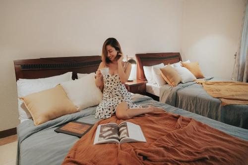 a girl sitting on a bed with a book at 150 Peakway Mountain Resort in Dalaguete