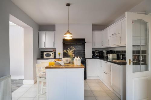 a kitchen with white cabinets and a counter top at Lovely 3 bedroom home in Rhos on Sea in Llandrillo-yn-Rhôs