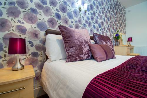 a bedroom with a bed with purple and purple pillows at The Richmond Bed and Breakfast - Adults only in Shanklin