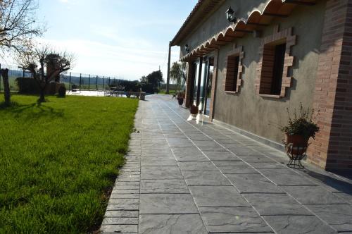 a stone walkway next to a building with a yard at Mas Piua in Girona
