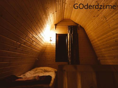 a bed in a wooden room with a light at GOderdzi Tkupebi in Goderdzi