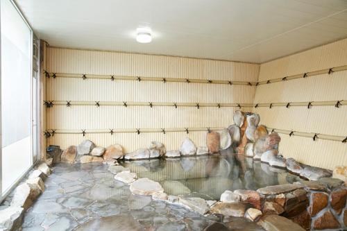Shirahama Onsen Kisyu Hanto في شيراهاما: تجمع مياه في غرفه بها صخور