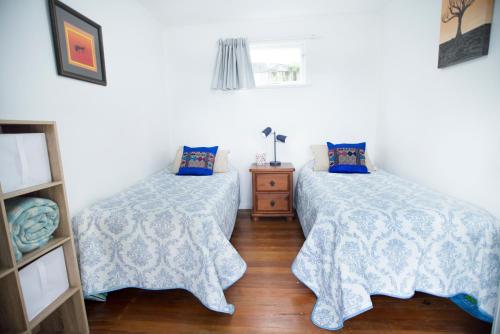 a bedroom with two beds and a wooden floor at Nigel's Crib - Coopers Beach Holiday Home in Coopers Beach