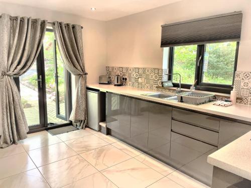 cocina con fregadero y algunas ventanas en BlueStone-Hot Tub-Woodlandlodges-Pembrokeshire-Tenby, en Carmarthen