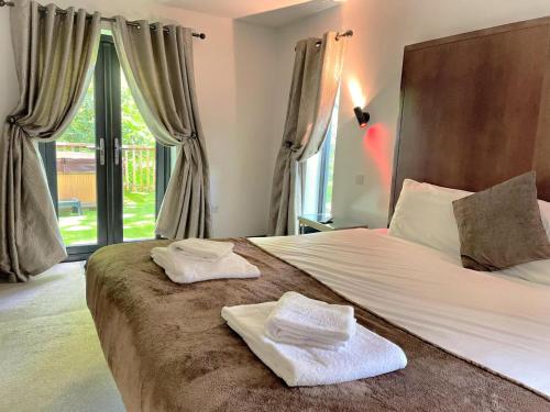 um quarto com uma cama grande e toalhas em BlueStone-Hot Tub-Woodlandlodges-Pembrokeshire-Tenby em Carmarthen