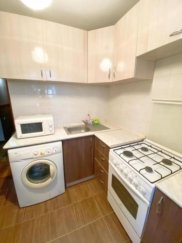 a kitchen with a stove and a washing machine at Квартира напротив Аэропорта in (( Turksib ))