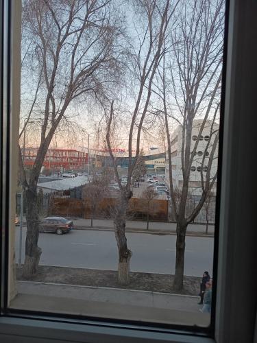 a window with a view of a parking lot with trees at Квартира напротив Аэропорта in Turksib