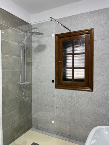 y baño con ducha acristalada y ventana. en Apartamento Garcey en Ajuy