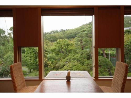 a table with a candle and two chairs in front of a window at Breezbay Shuzenji Hotel in Izu