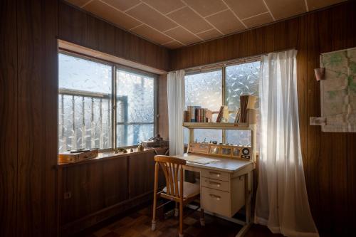a desk and a chair in a room with a window at 神倉書斎 [Kamikura-Hideaway] in Shingu