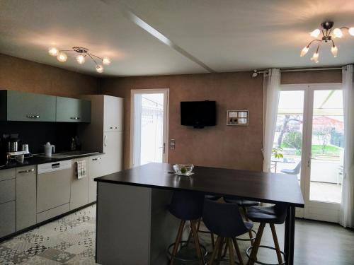 - une cuisine avec un comptoir noir et des chaises dans l'établissement Maison plain pied avec jardin, terrasse et veranda, à Cognac