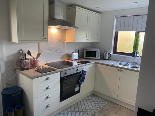 a kitchen with white cabinets and a stove top oven at The Wee house at the cottage in Annan