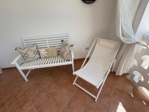 a white bench and a chair in a room at Villa Connie in Serranova