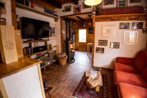 a living room with a red couch and a television at Chalet Relax Tra Le Vigne in Forni di Sotto