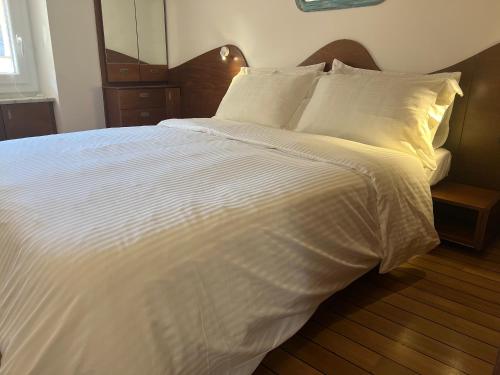a large white bed with white sheets and pillows at Elegant apartment with sea view in Monterosso al Mare